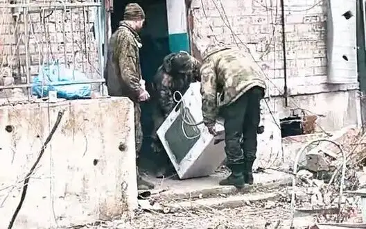 Three occupiers carrying washing machine along street of occupied and destroyed Avdiivka. VIDEO